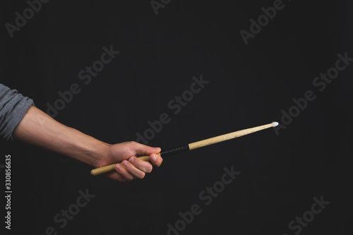 Hand holds drumstick in the dark. copy space