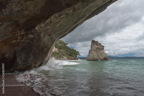 Waves crashing under the arch of Cathedral Cove, New Zealand