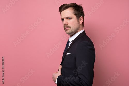 hansdsome serious man with mustache and suit lookign at camera confident. photo