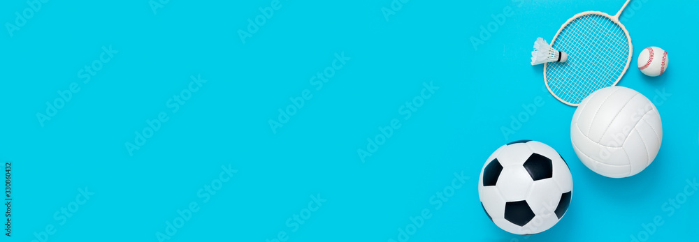 Assorted sports equipment including a basketball, soccer ball, volleyball, baseball, badminton racket on a light blue background Assorted sports equipment including a basketball, soccer ball, volleyball, baseball, badminton racket on a light blue background