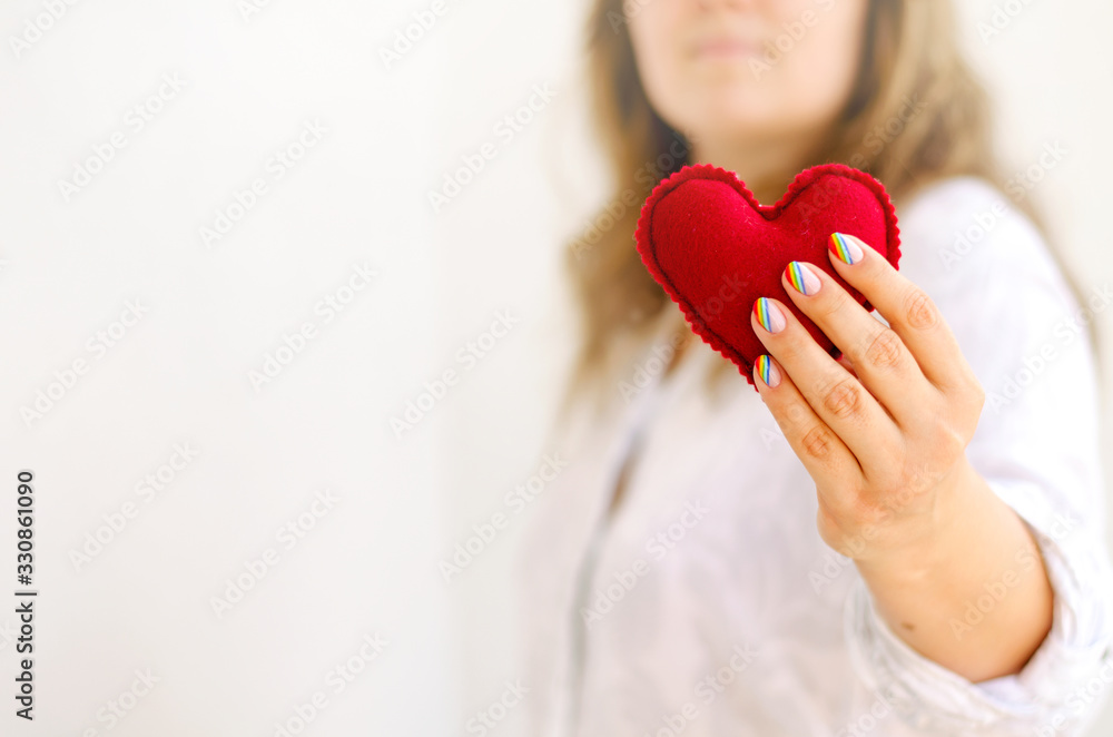 Red felted heart in femaile hands with rainbow manicure. Love, valentine, lgbt, pride concept Red felted heart in femaile hands with rainbow manicure. Love, valentine, lgbt, pride concept