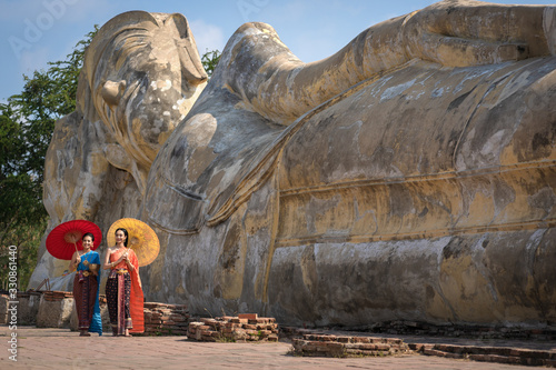 Bilde på lerret Asian Thai women walking with umbrella in front of the Reclining Buddha, Pretty