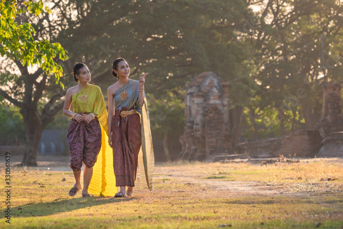 Asian women walking at the historical ancient temple Ayutthaya, Thailand, Pretty girl wearing in Thai traditional dress costume according Thai culture Thailand