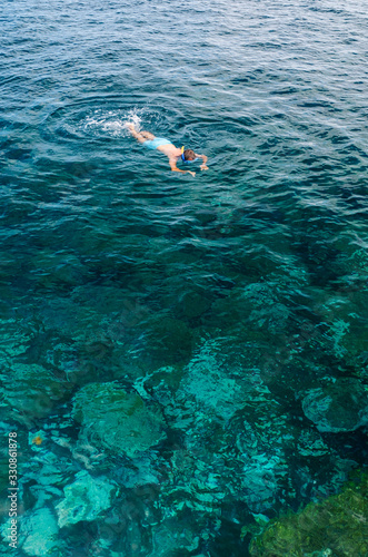 a man dives with glasses and tube and bathes in the sea with turquoise blue color