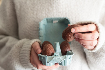 Close up of woman holding easter chocolate egg from egg carton