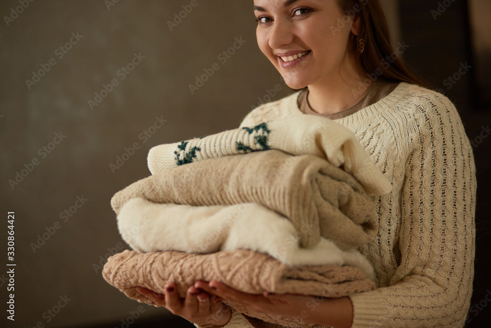 Stack of knitted clothes in young female hands