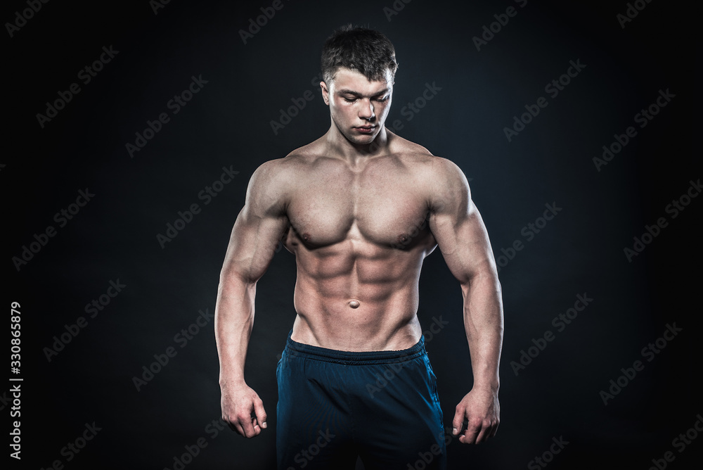 Sexy young athlete posing on a black background in the Studio. Fitness, bodybuilding Sexy young athlete posing on a black background in the Studio. Fitness, bodybuilding