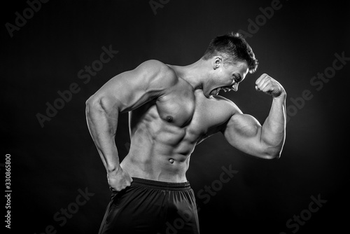 Sexy young athlete posing on a black background in the Studio. Fitness, bodybuilding, black and white