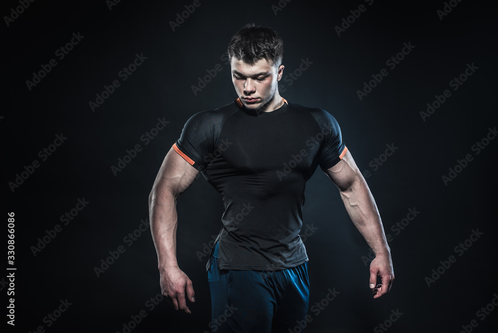 Naklejka premium Sexy young athlete posing on a black background in the Studio. Fitness, bodybuilding