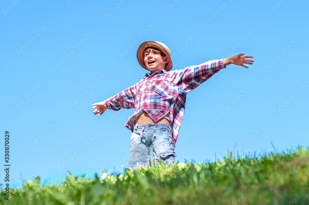 A boy standing on top of a mountain with outstretched arms. Chil A boy standing on top of a mountain with outstretched arms. Chil