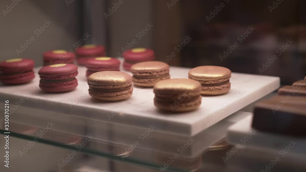 Zoom in of macaron and several chocolate small cakes behind the glass, on the counter in coffee shop. Small chocolate cakes lying on the showcase in the shop Zoom in of macaron and several chocolate small cakes behind the glass, on the counter in coffee shop. Small chocolate cakes lying on the showcase in the shop