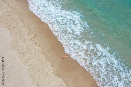 girl in a red bathing suit lies on the shore of a sandy beach with turquoise water yalong bay photo