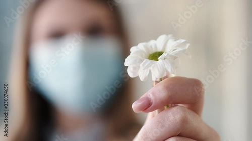 Woman dostor in a disposable mask is holding a camomile in a test tube. photo