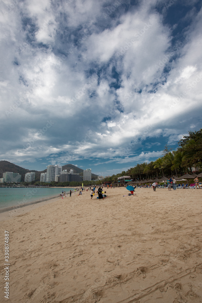 Hainan beautiful sandy bay with palm trees and beach umbrellas Hainan beautiful sandy bay with palm trees and beach umbrellas
