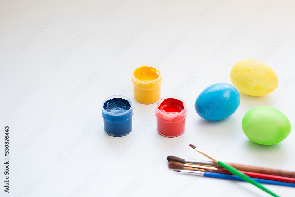 Painted Easter eggs, cans of paint, brushes on a white surface Painted Easter eggs, cans of paint, brushes on a white surface