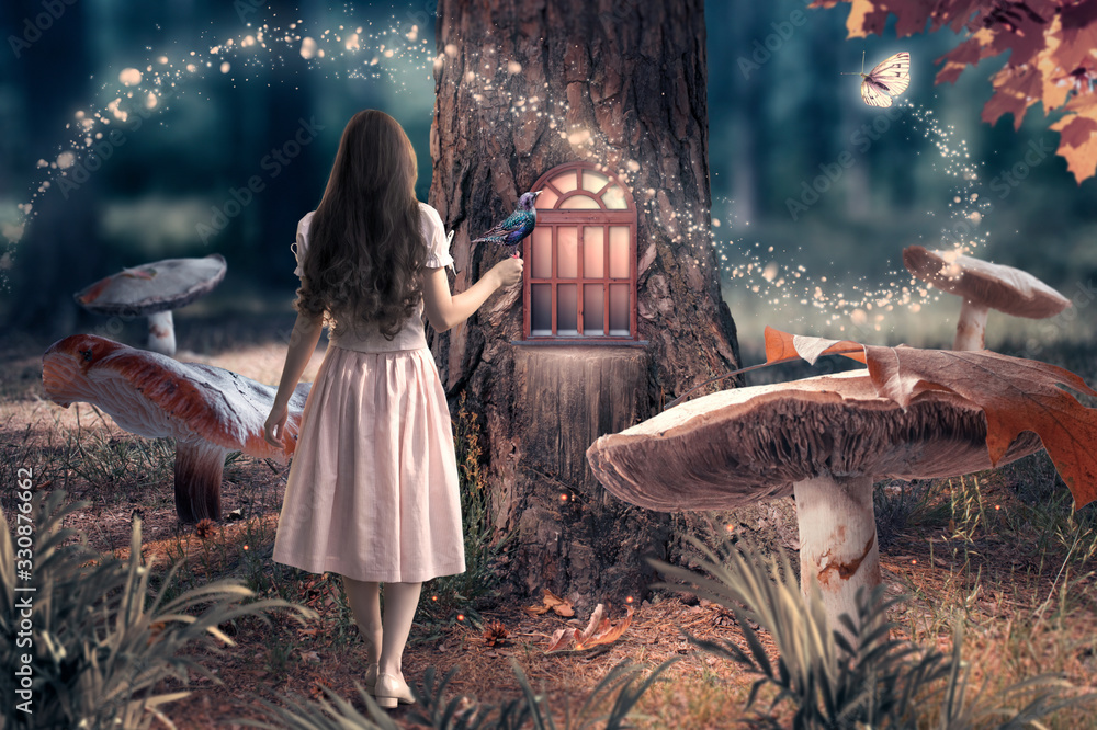 Fototapeta premium Dziewczyna w sukience z ptakiem w dłoni w fantazji zaczarowany bajkowy las z gigantycznymi grzybami, magiczne lśniące okno w dziupli sosny i latający magiczny motyl opuszczający ścieżkę ze świetlistymi iskierkami