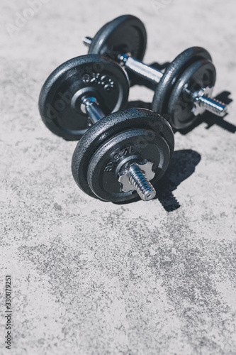 keeping fit and exercising outdoor, set of heavy dumbbells on concrete path in a backyard