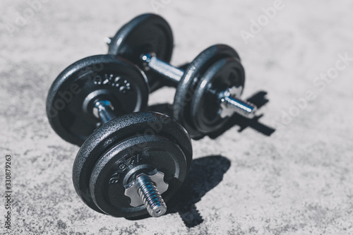 keeping fit and exercising outdoor, set of heavy dumbbells on concrete path in a backyard