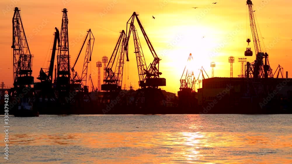 Varna sea port at sunset, silhouettes of birds, industrial cranes and cargo ships, Bulgaria. Varna sea port at sunset, silhouettes of birds, industrial cranes and cargo ships, Bulgaria.