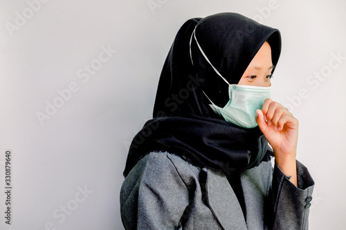  The concept of coronavirus and air pollution. portrait of young Asian girl wearing a mask to protect covid-19 and showing closing her mouth when coughing. Symptoms of the coronavirus virus and epidem photo