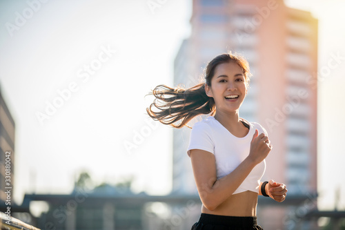 Fotografie Asian Young fitness sport woman running  and smiling on city road