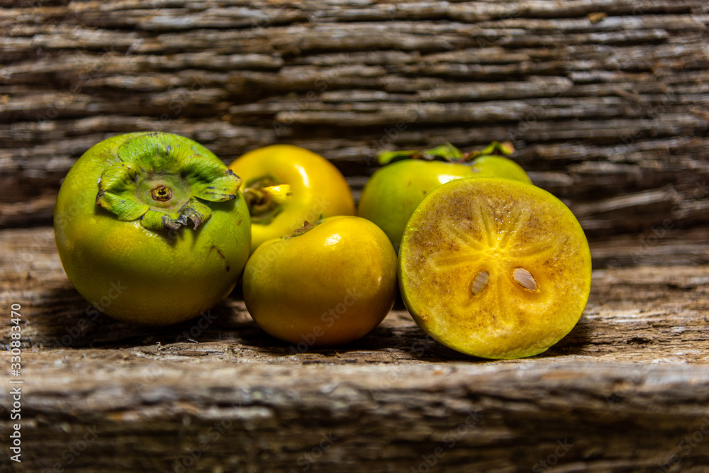 Persimmon fruits fresh and in halves on wooden construction background Persimmon fruits fresh and in halves on wooden construction background