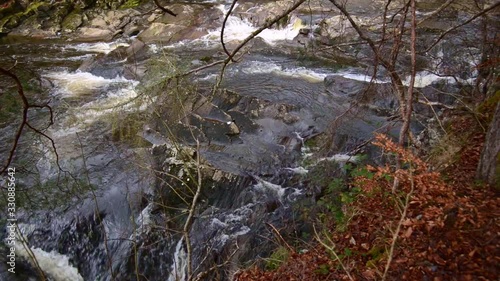 Wide angle tilt up showing a cascade like river flowing . In autmn. Scotland photo