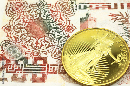 A macro image of a beige Algerian dinar note with a gold coin.  Shot close up. photo