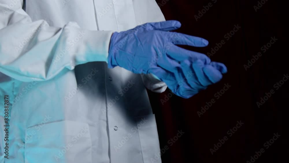 Doctor removing latex gloves in dramatic lighting Doctor removing latex gloves in dramatic lighting