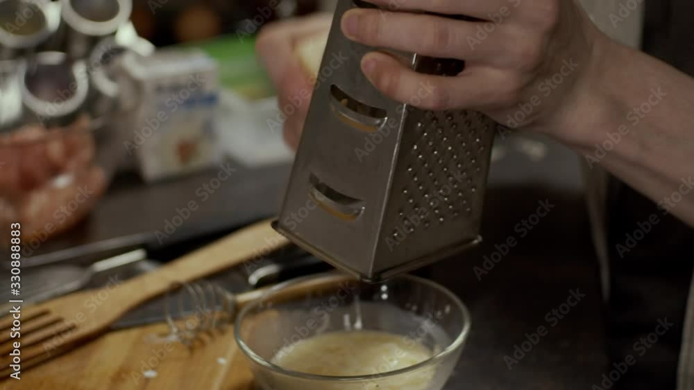 Grinding cheese with grater in bowl, shallow depth of field, slow motion Grinding cheese with grater in bowl, shallow depth of field, slow motion