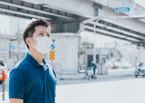 Young man standing beside sreet wearing mask for protection from Covid-19 and PM 2.5 dust. Looking upward
