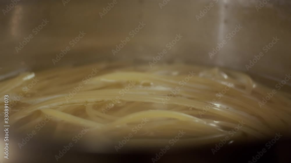 Boiling water with spaghetti in pan, slow motion, shallow depth of field Boiling water with spaghetti in pan, slow motion, shallow depth of field