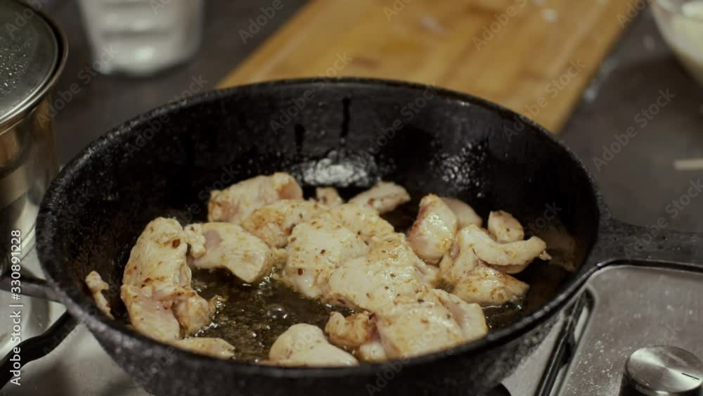 Chicken meat in frying pan, process of frying in oil, shallow depth of field, slow motion Chicken meat in frying pan, process of frying in oil, shallow depth of field, slow motion