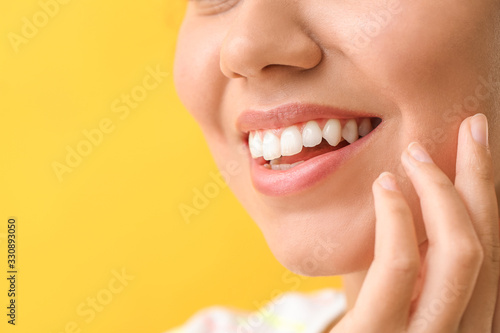 Happy woman with healthy teeth on color background  closeup