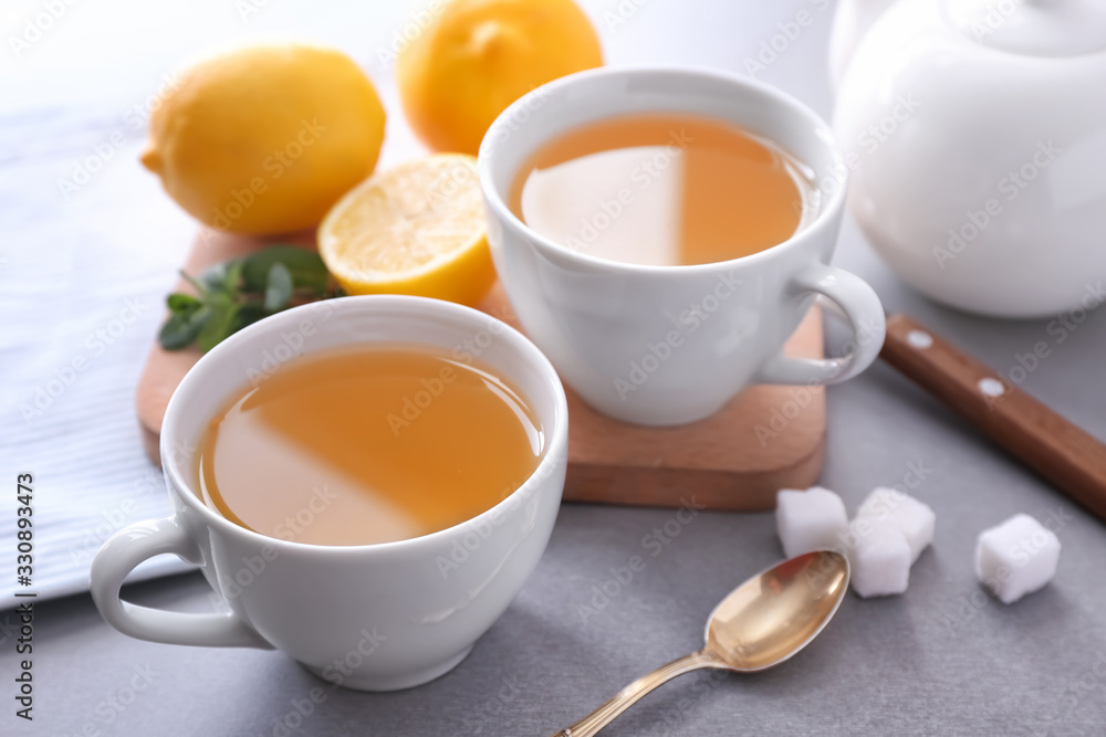 Cups of hot tea with lemon on grey background Cups of hot tea with lemon on grey background
