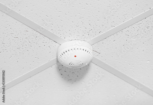 Modern smoke detector on ceiling photo