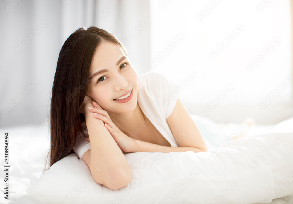 Young smiling woman lying in bed in bedroom Young smiling woman lying in bed in bedroom