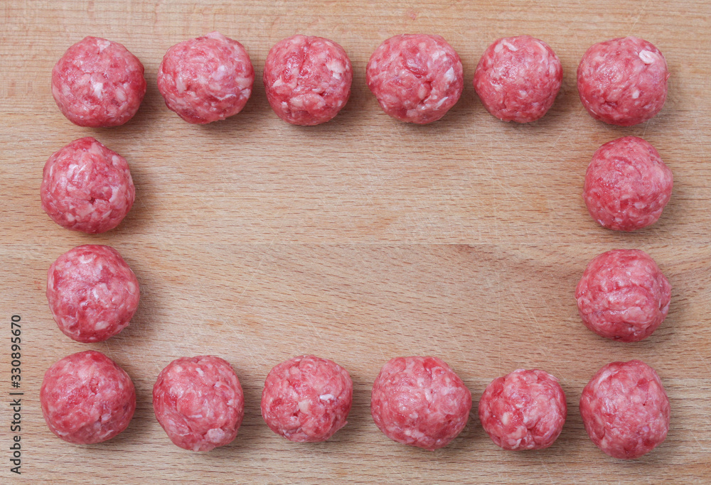 Raw beef meatballs on a wooden Board. Frame, space for text