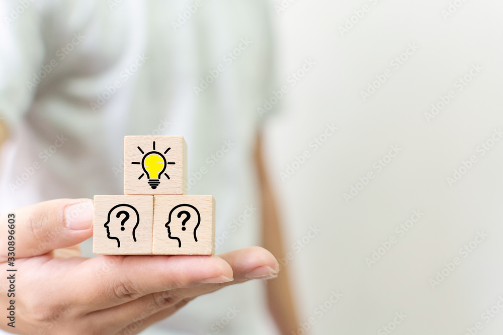 Concept creative idea and innovation. Hand holding wooden cube block with light bulb and head human symbol icon Concept creative idea and innovation. Hand holding wooden cube block with light bulb and head human symbol icon