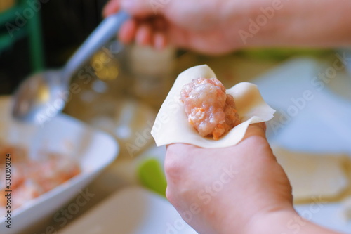 Close up and selective focus of hands cooking homemade making of Traditional chinese food dumpling called Shumai in Thailand called kanom jeep. Cooking by steam in bamboo basket. film grain style.