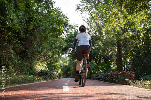 Woman cycling on bike path at park on sunny day © lzf