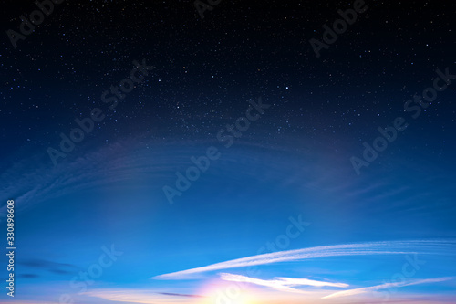 Sunset sky with orange setting sun and white clouds landscape against bright star on black universe background Wide panorama view of stars in space nature at dark time Starry night at night wallpaper © vaalaa