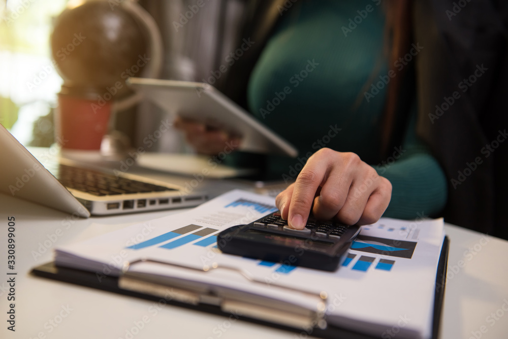 Hand business doing finances and calculate on desk about cost using on smartphone and tablet as concept Hand business doing finances and calculate on desk about cost using on smartphone and tablet as concept