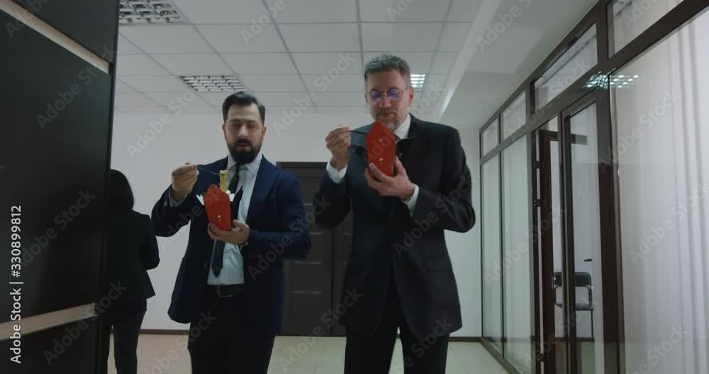 Businessmen chatting and eating in office corridor Businessmen chatting and eating in office corridor