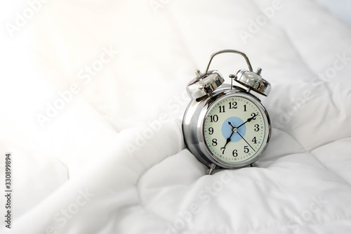 Clock alarm on bed in bedroom in the morning.