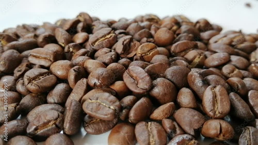 Roasted coffee beans drop to coffee bean pile on white floor and shaking by wind blow. Roasted coffee beans drop to coffee bean pile on white floor and shaking by wind blow.