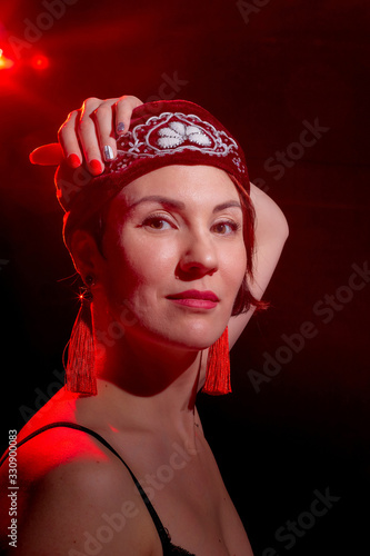Portrait of a young beautiful woman in Tatar national folk red hat and a red dress. Fashion photo shoot in low key