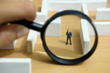 Business strategy conceptual photo - Miniature of businessman looking for solution on a labyrinth maze
