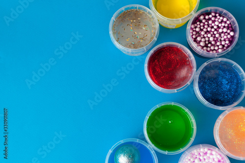 Flat lay with jars with slime. Multi-colored on a blue background. Top view copy space. Kids crafts concept. photo