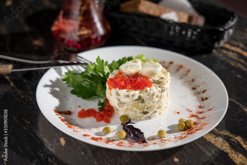 Olivier salad with red caviar from green peas of pickles, restaurant serving, bar serving